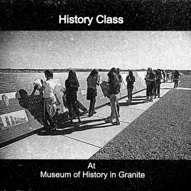 Engraving of a group of students learning from a monument at the History of Humanity in Granite engraved on Marble Panel at Maze of Honor