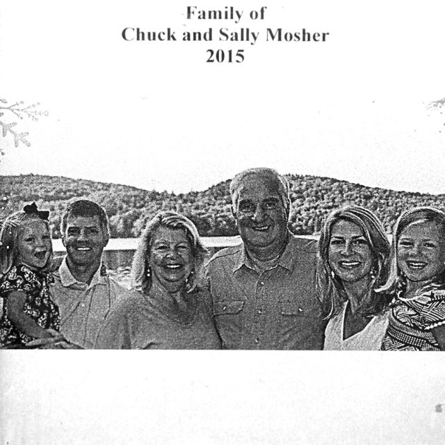 Smiling man and woman with family smile in front of a hilly backdrop
