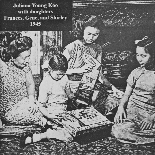 Image from 1945 of two asian mothers sitting on the floor with their daughters