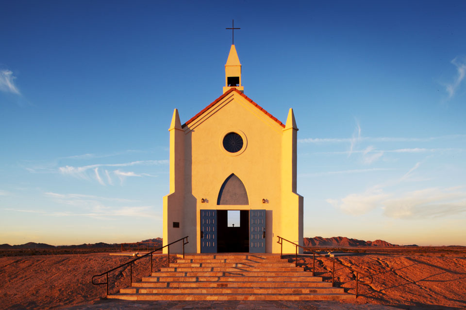 The Church on the Hill lit by the setting sun with the mountains of California in the background