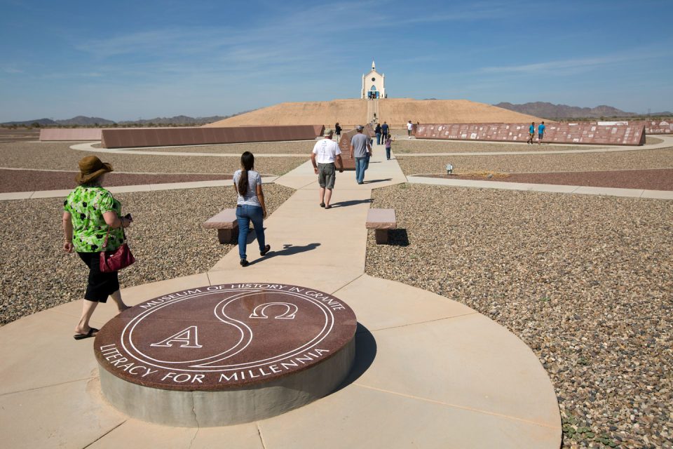 Visitors to the Museum of History in Granite walk through the monuments toward the hill of prayer in Felicity, California
