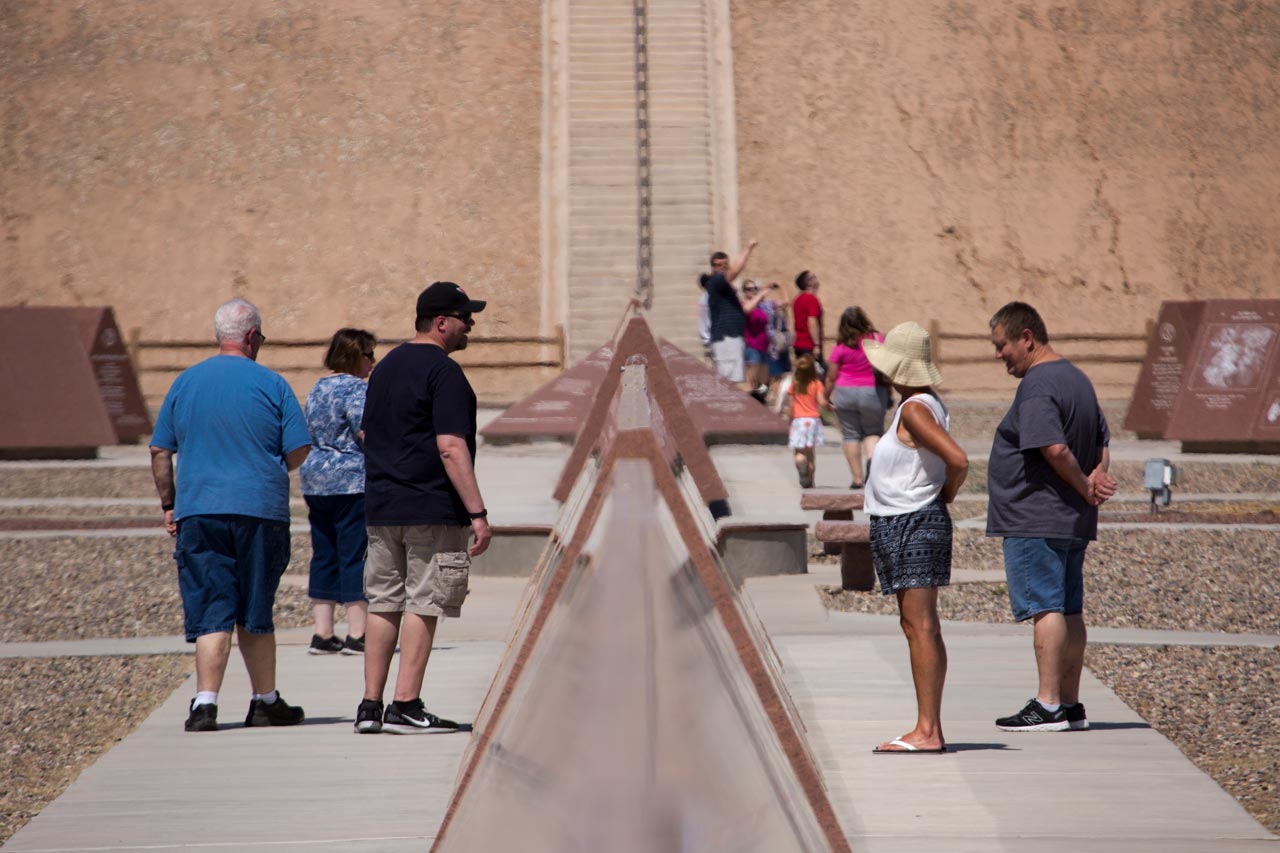 Visitors to the History of Humanity in Granite stand on either side of a monument