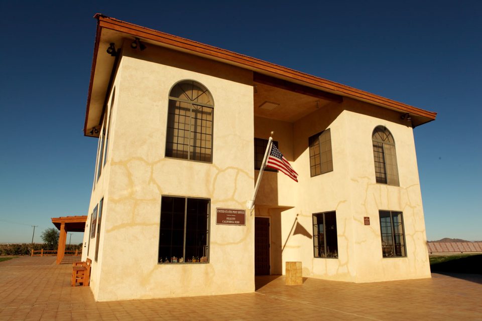 White stone building with sienna colored roof which serves as the United States Post Office of Felicity California