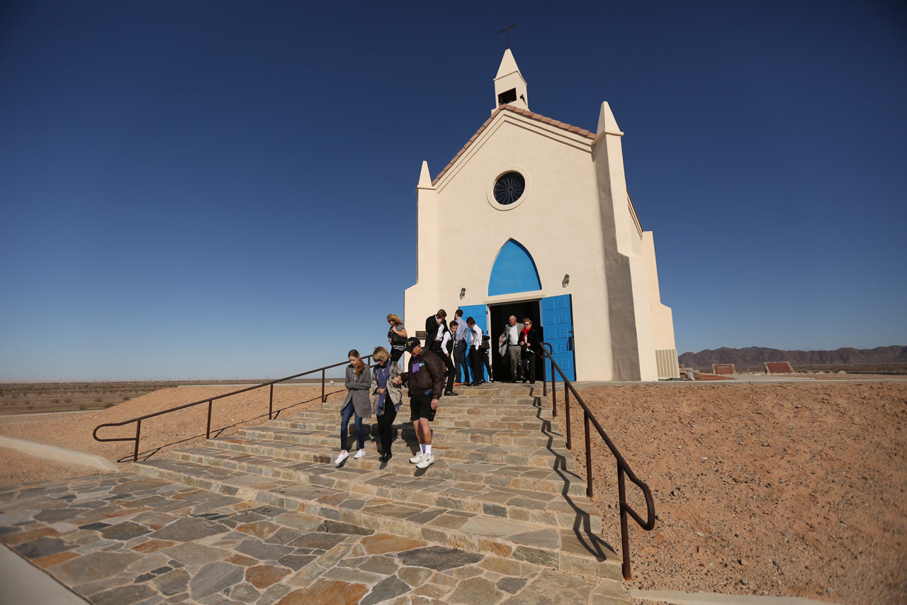 Group of people walking down the entry way steps of the white church on the hill in Felicity California