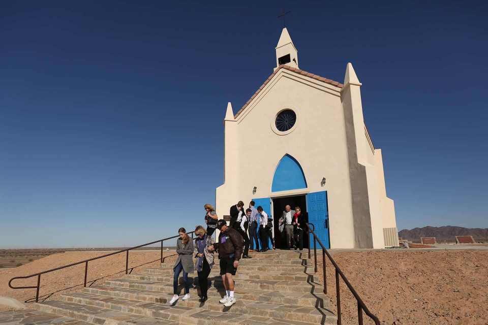 Group of people walking down the entry way steps of the white church on the hill in Felicity California